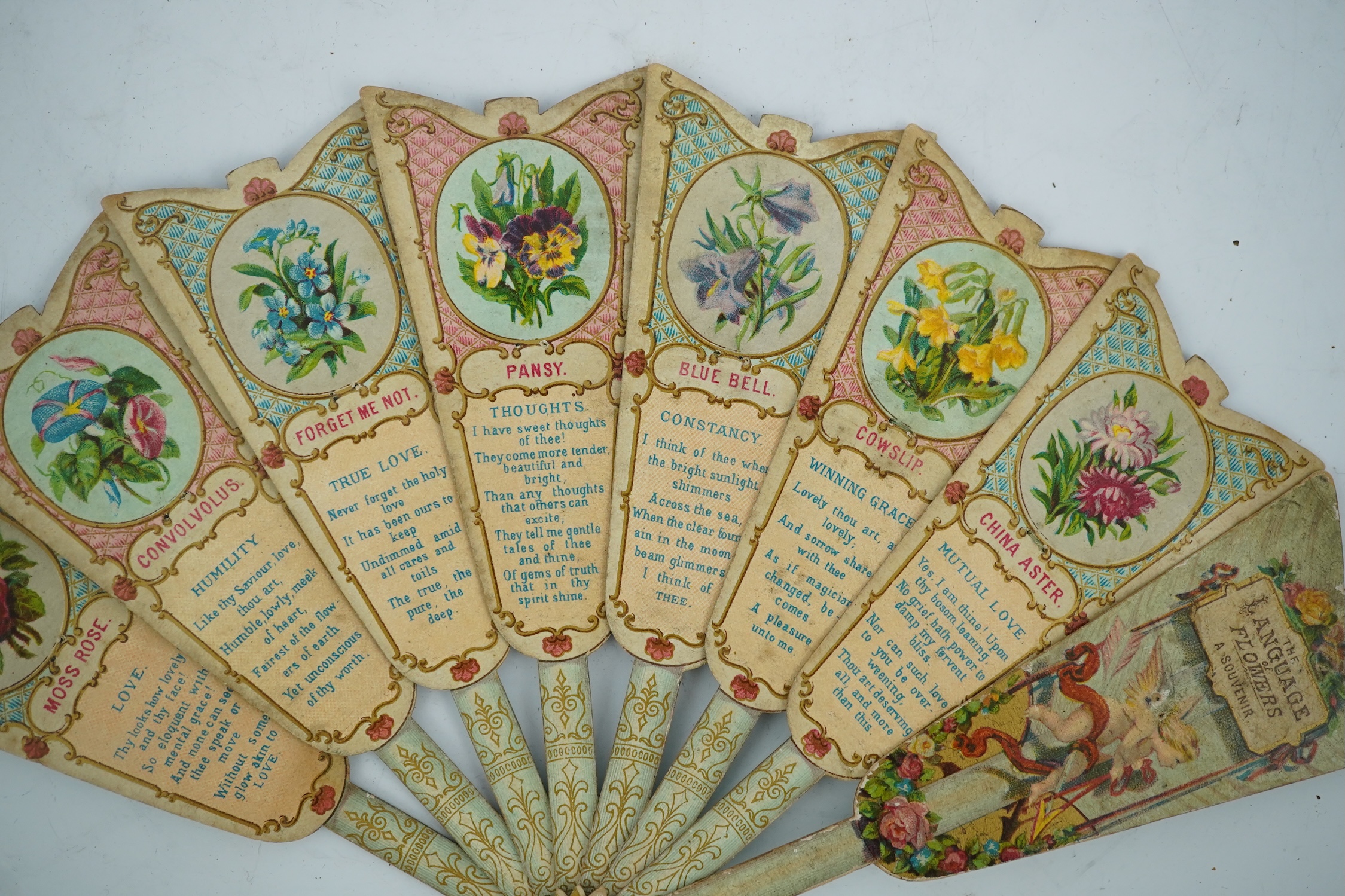 Three novelty fans with a mixed Brussels lace fan and black lace fan, a small language of love in flowers fan, a paper windmill advertising French Café fan, a carved cream Bakelite fan, a black and gilt, lace and sequin